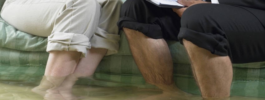 Couple with pants rolled up standing in flooded room