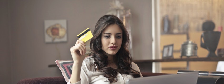 Woman holding credit card looking at computer
